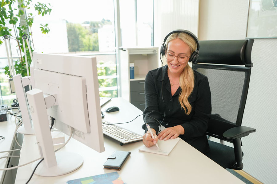 Person am Schreibtischarbeitsplatz Person am Schreibtisch, die sich beim Telefonieren Notizen macht